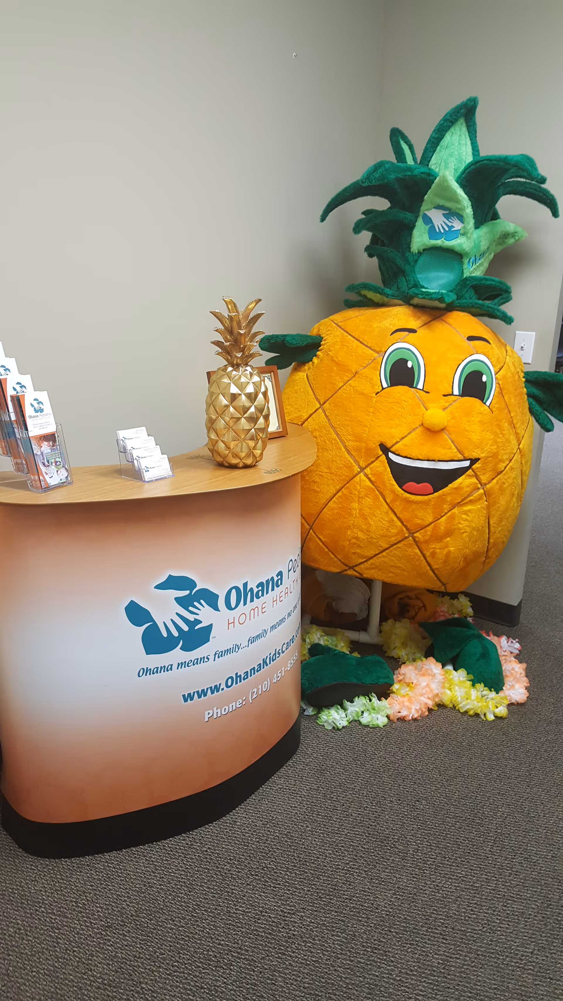 Reception desk with Ohana Pediatric Home Health branding and a pineapple mascot in a lobby.