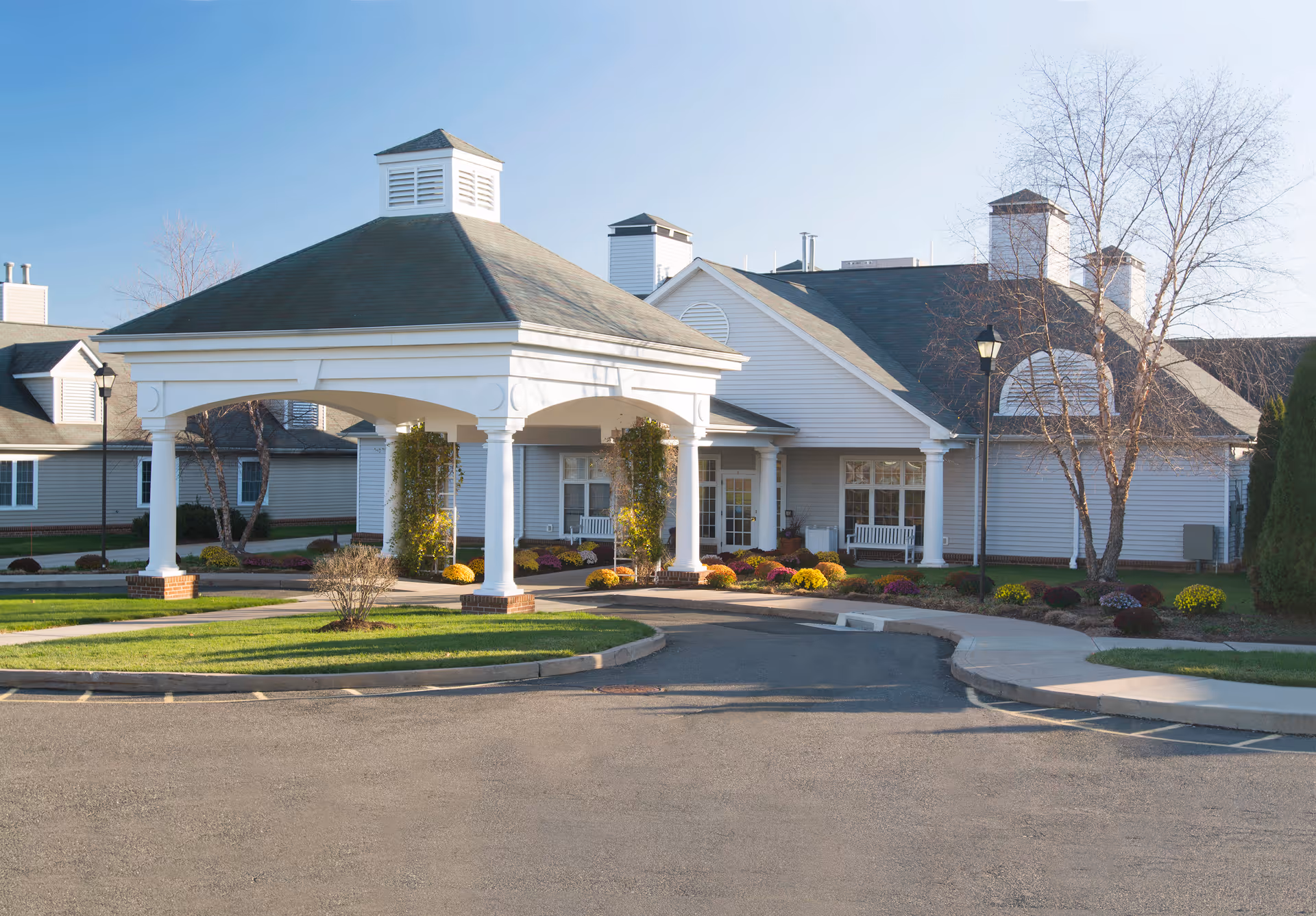 White building with porte-cochère entrance, columns, and landscaped front grounds.
