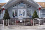 Front exterior view of a light-blue assisted living entrance with wreaths.