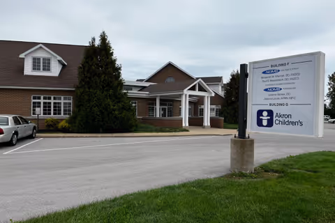 Exterior view of a brick facility with a parking lot and a large sign.
