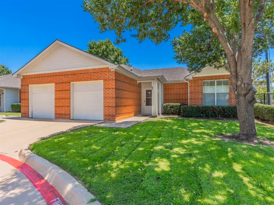 Brick single-story building with two-car garage and manicured lawn.