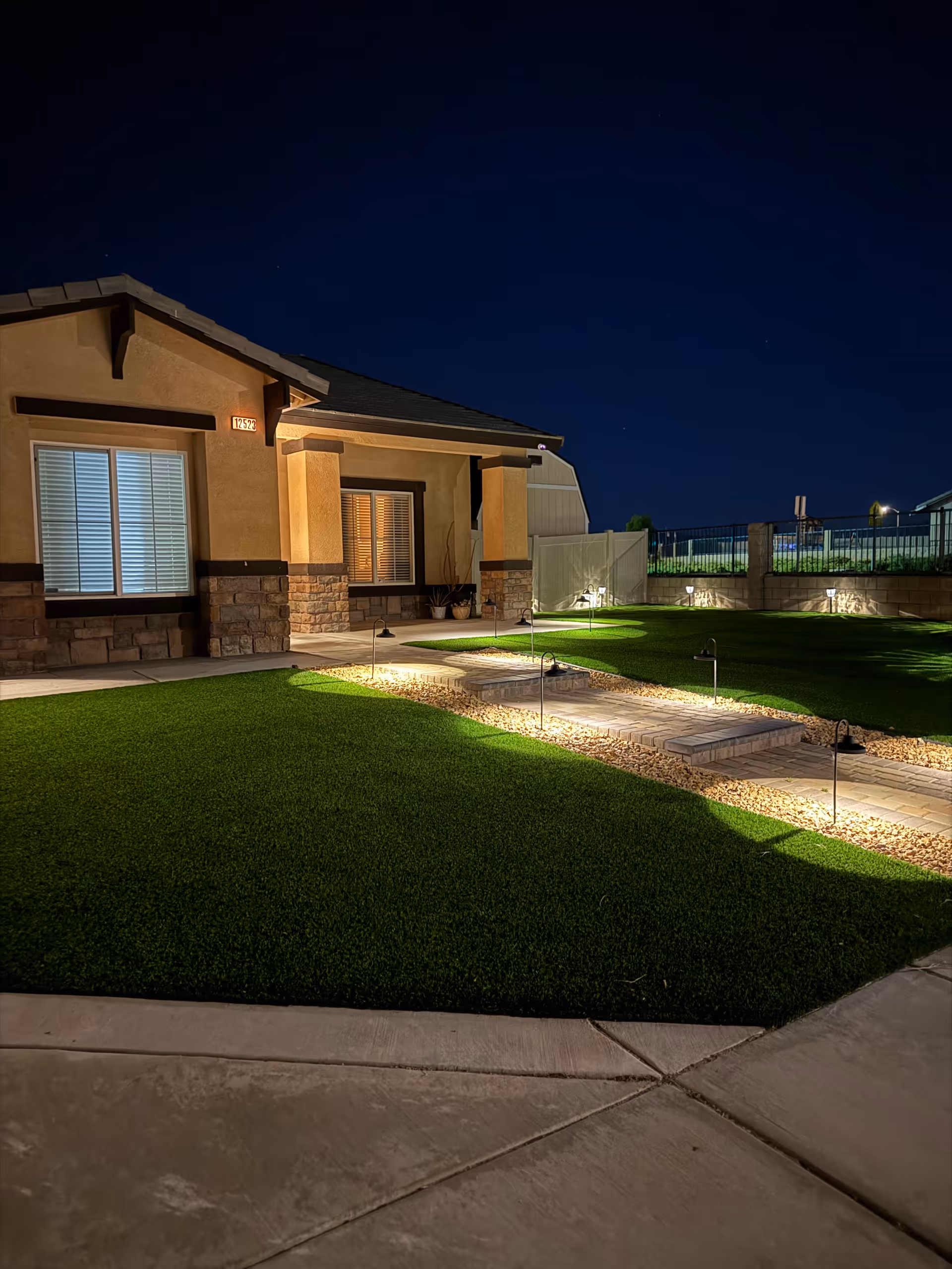 Nighttime exterior of Oakwood Court Residential Home with illuminated walkway and manicured lawn.