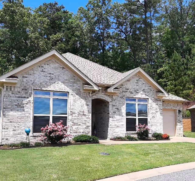 Stone façade senior living facility with arched entrance and manicured front yard.