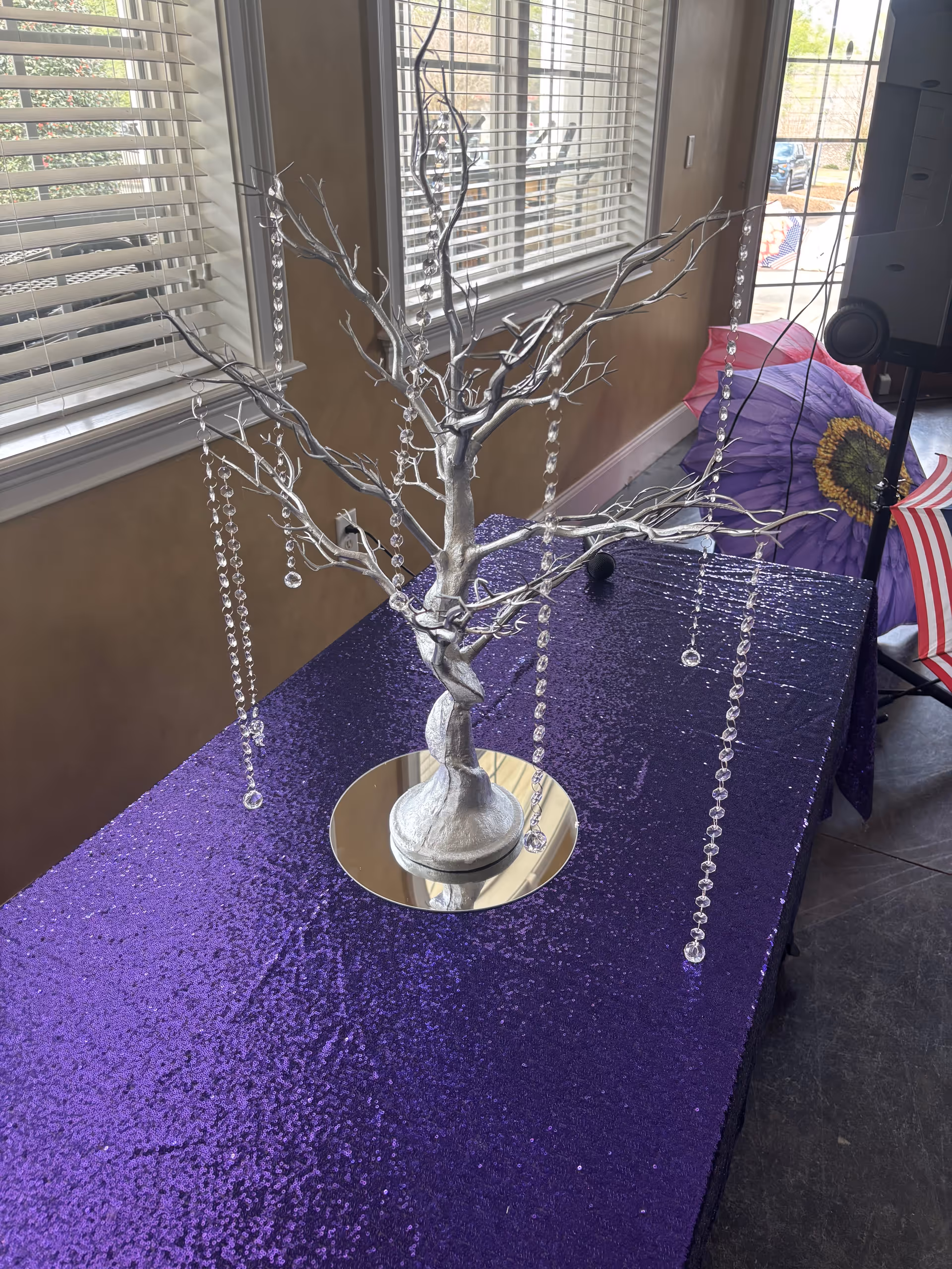 Interior room with a silver crystal tree centerpiece on a purple glitter table.