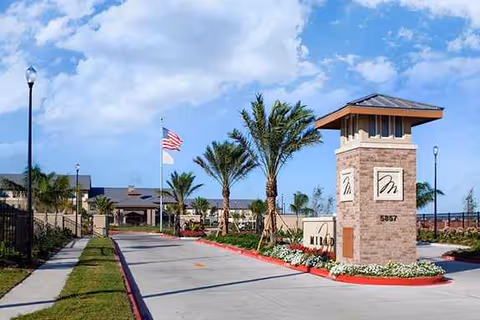 Front entrance of Mirador Retirement Community with palm trees, flag, and signage.