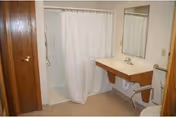 Bathroom interior with shower, white curtain, sink, mirror, and wooden door.