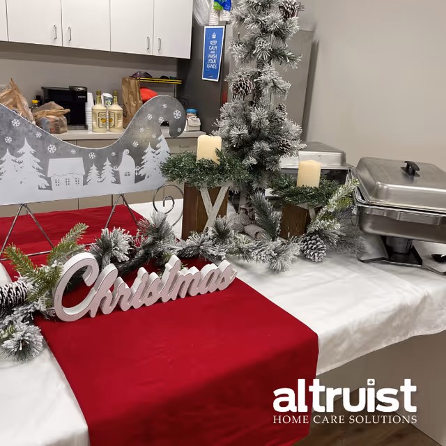 A Christmas display sits on a table with candles and a red runner.