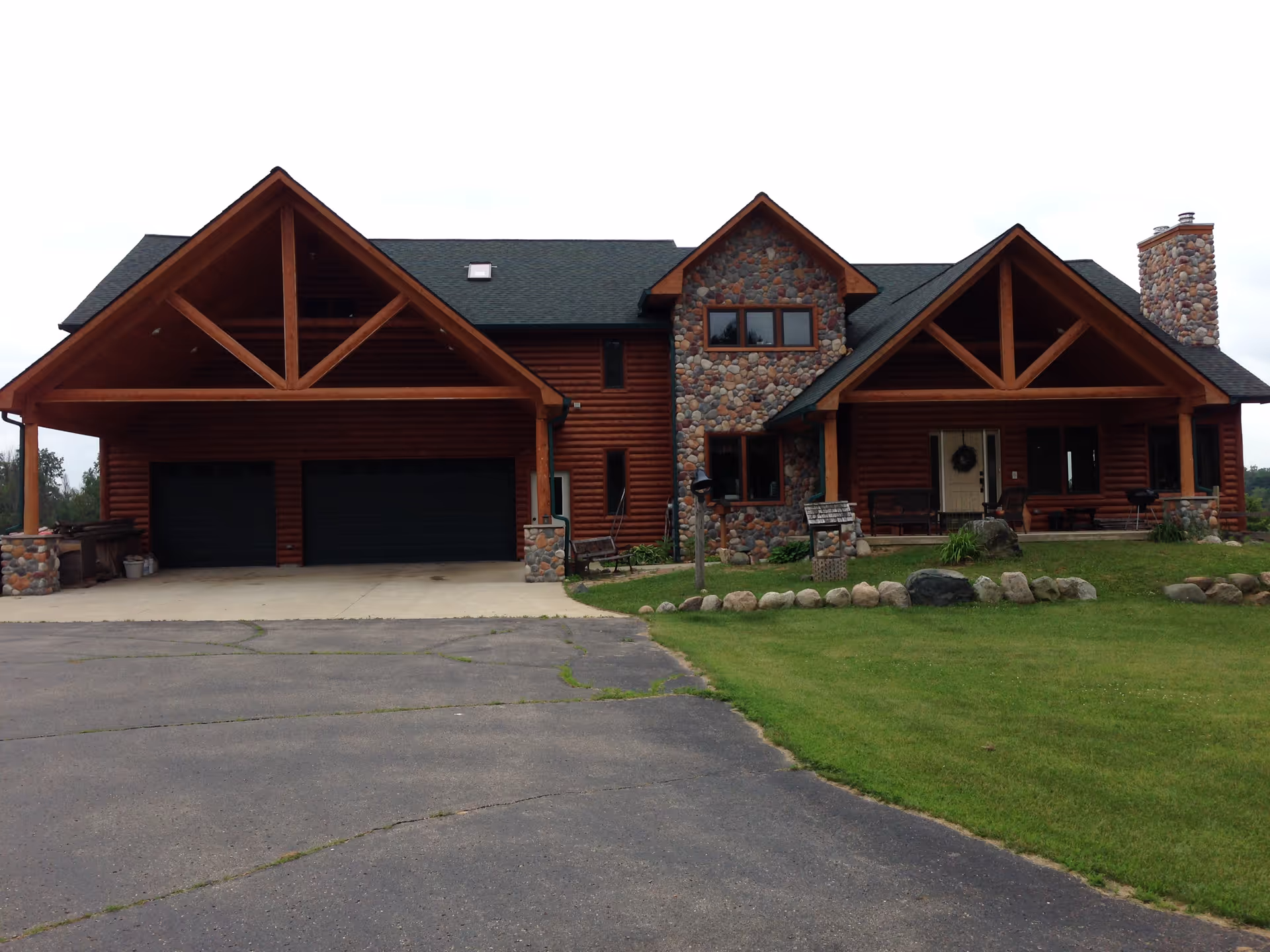 Log-style lodge with stone accents, attached garages, and a manicured front lawn.