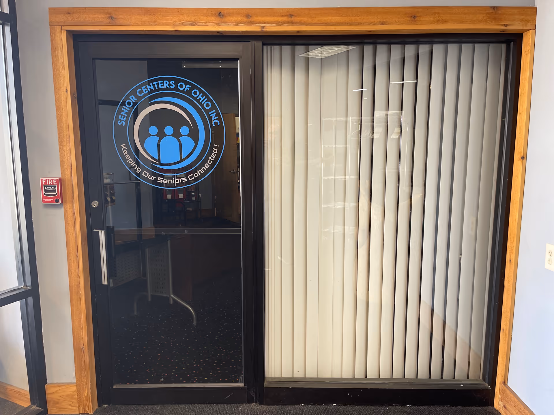 Interior doorway with Senior Centers of Ohio logo, glass pane, and vertical blinds.