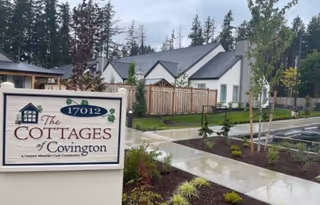 Front exterior view of The Cottages of Covington with sign and landscaped walkway.
