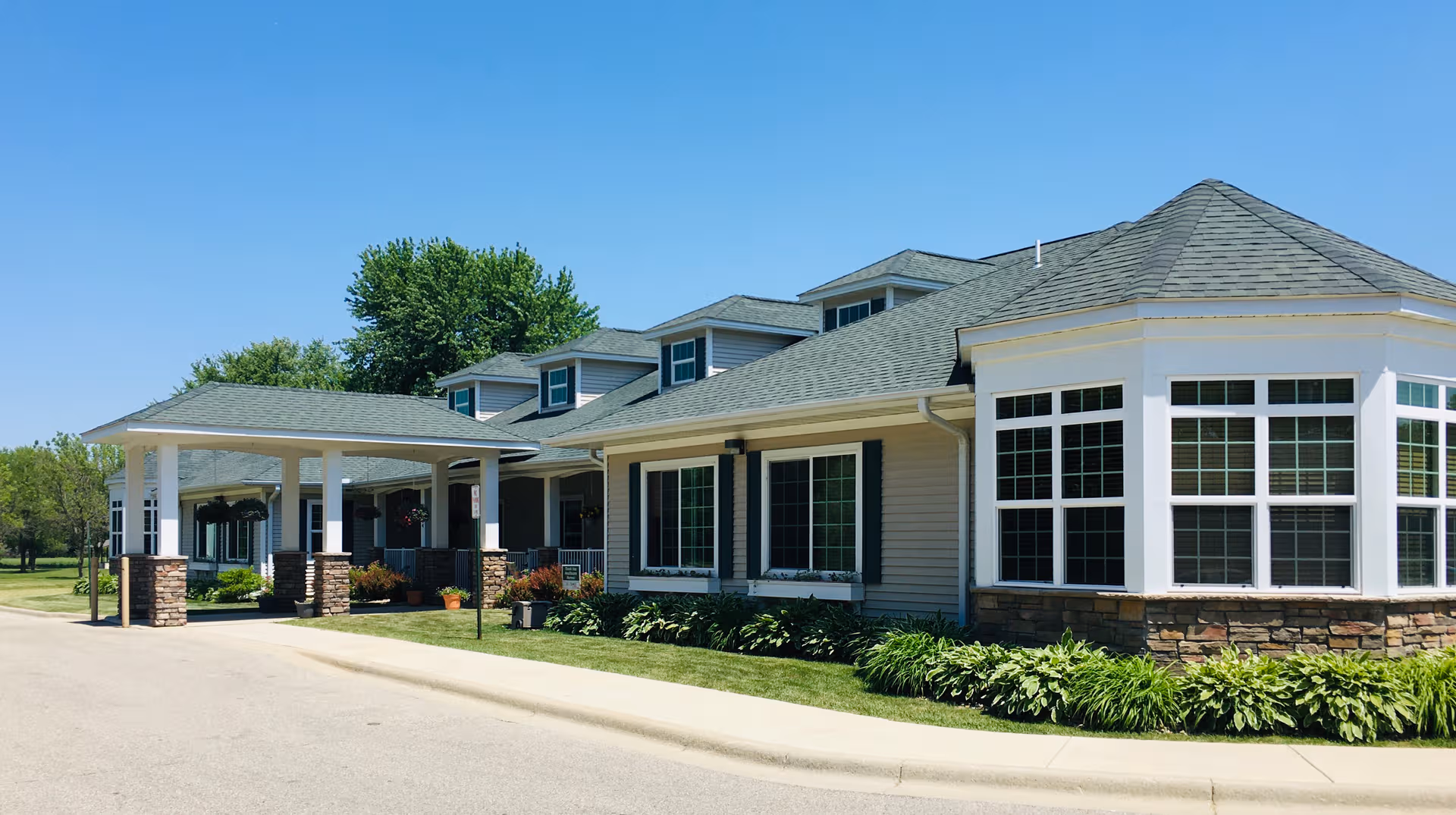 A single-story senior living facility exterior with a covered entrance and bay windows.