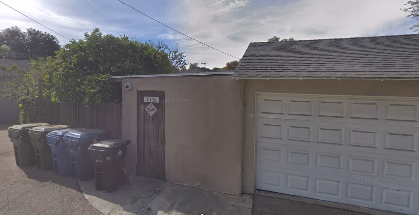 Exterior of a beige building with a small door and a large white garage door.