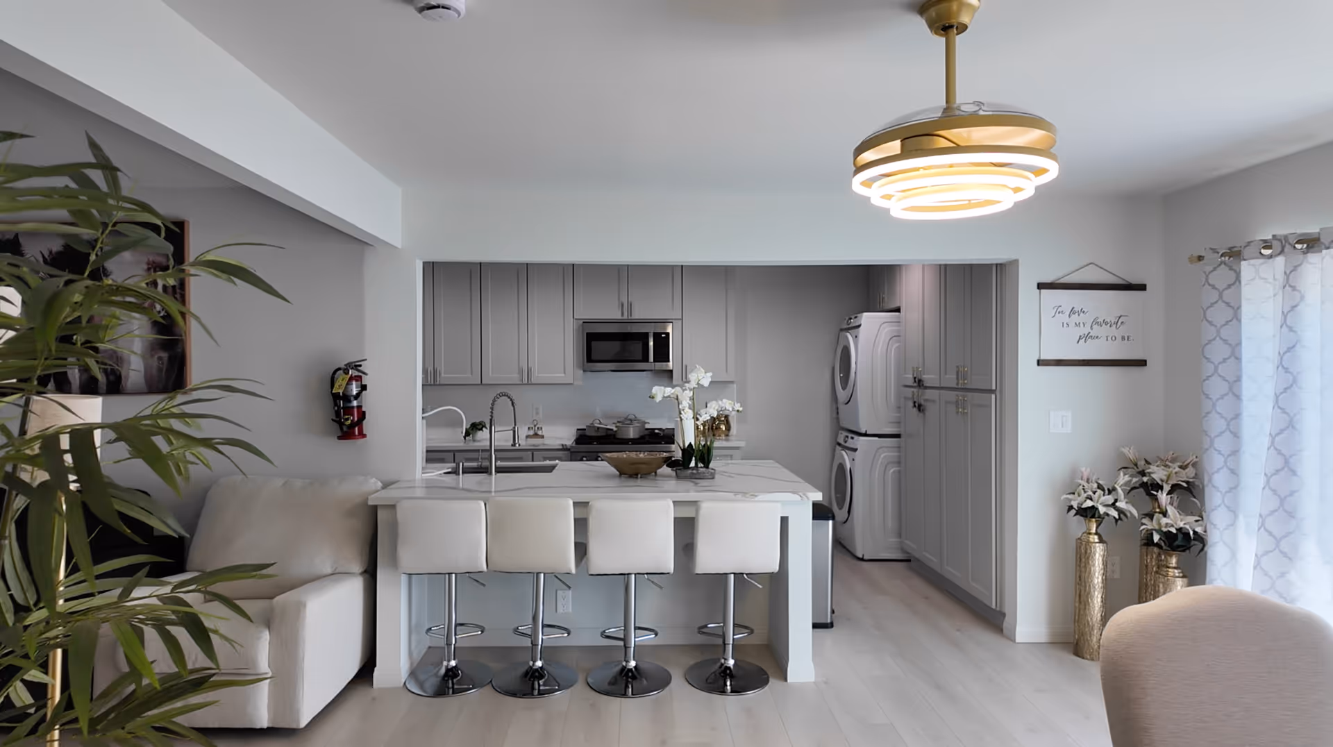 Open-concept kitchen with island, bar stools, and a living area.
