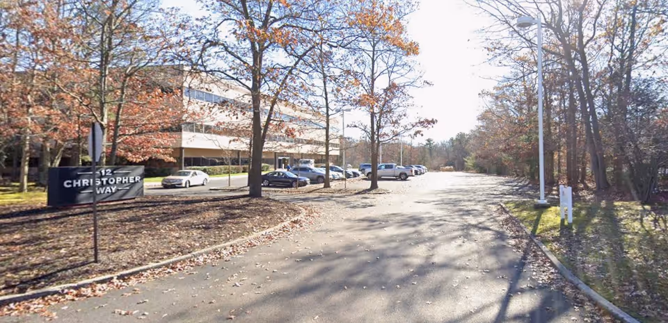 Exterior view of a senior living facility with a parking lot and trees.