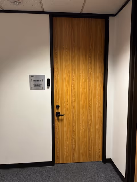 Wooden door in a hallway against beige walls with a plaque.