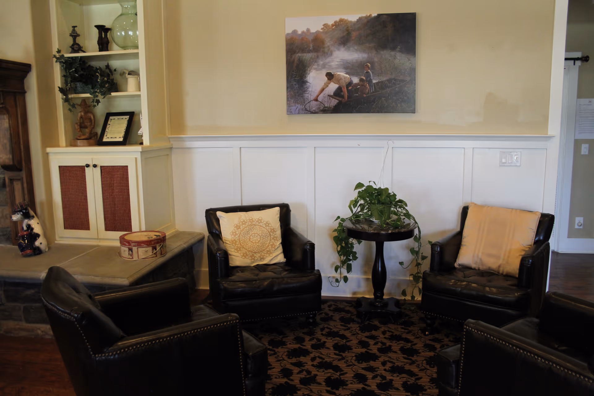 Main lounge area with black leather chairs, plant, rug, and wall artwork.