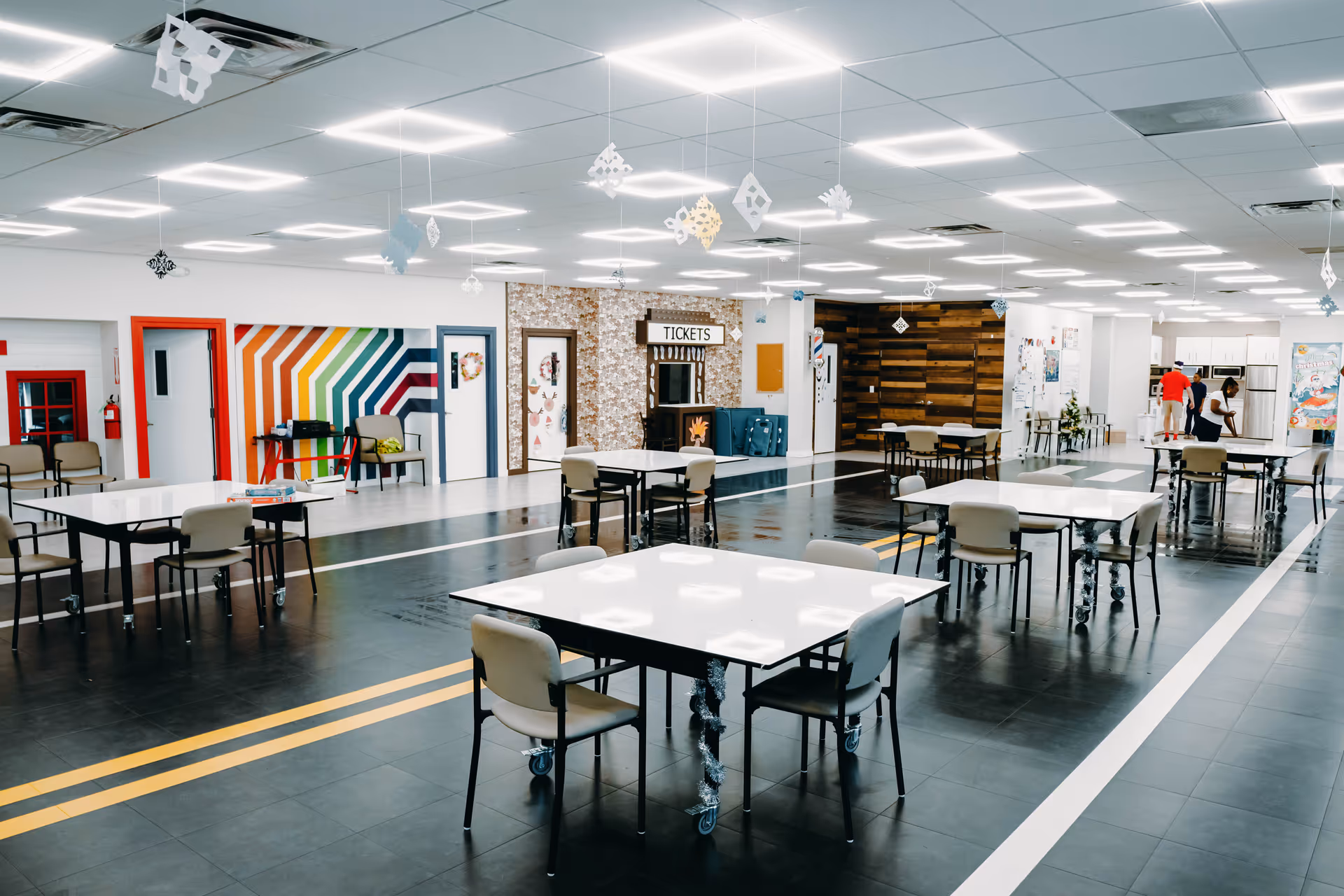Bright indoor multipurpose room with white tables on wheels and colorful wall accents.