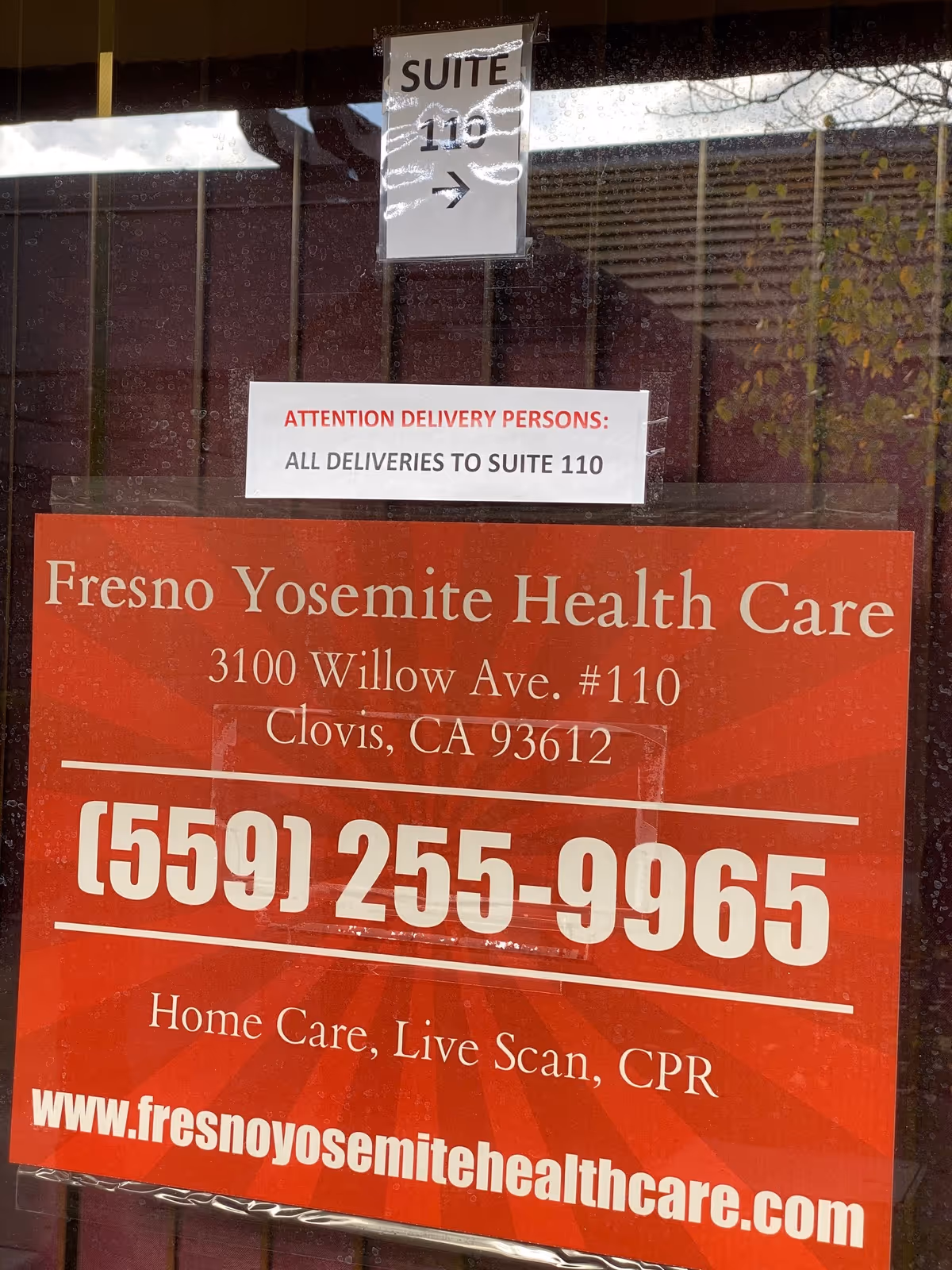Red Fresno Yosemite Health Care sign with address and phone number in a storefront window