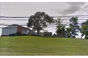 Exterior view of Mary Ellen Homes on a grassy hill with trees and power lines.
