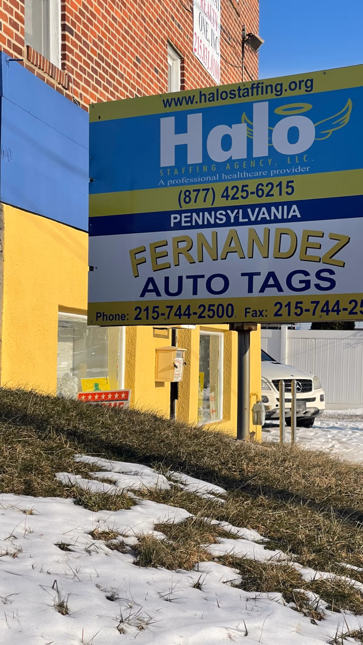 Bright Halo Staffing Agency signboard mounted on a yellow building exterior with snow on ground