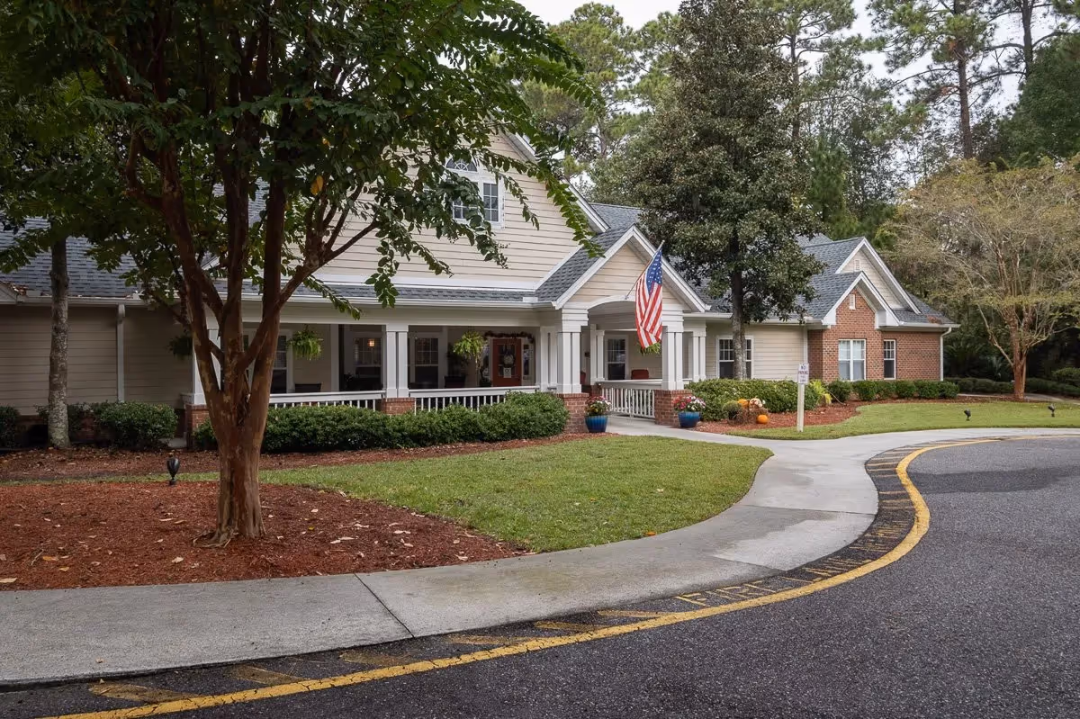 Front view of Harbor Cove Memory Care building with porch, flag, and curved driveway.
