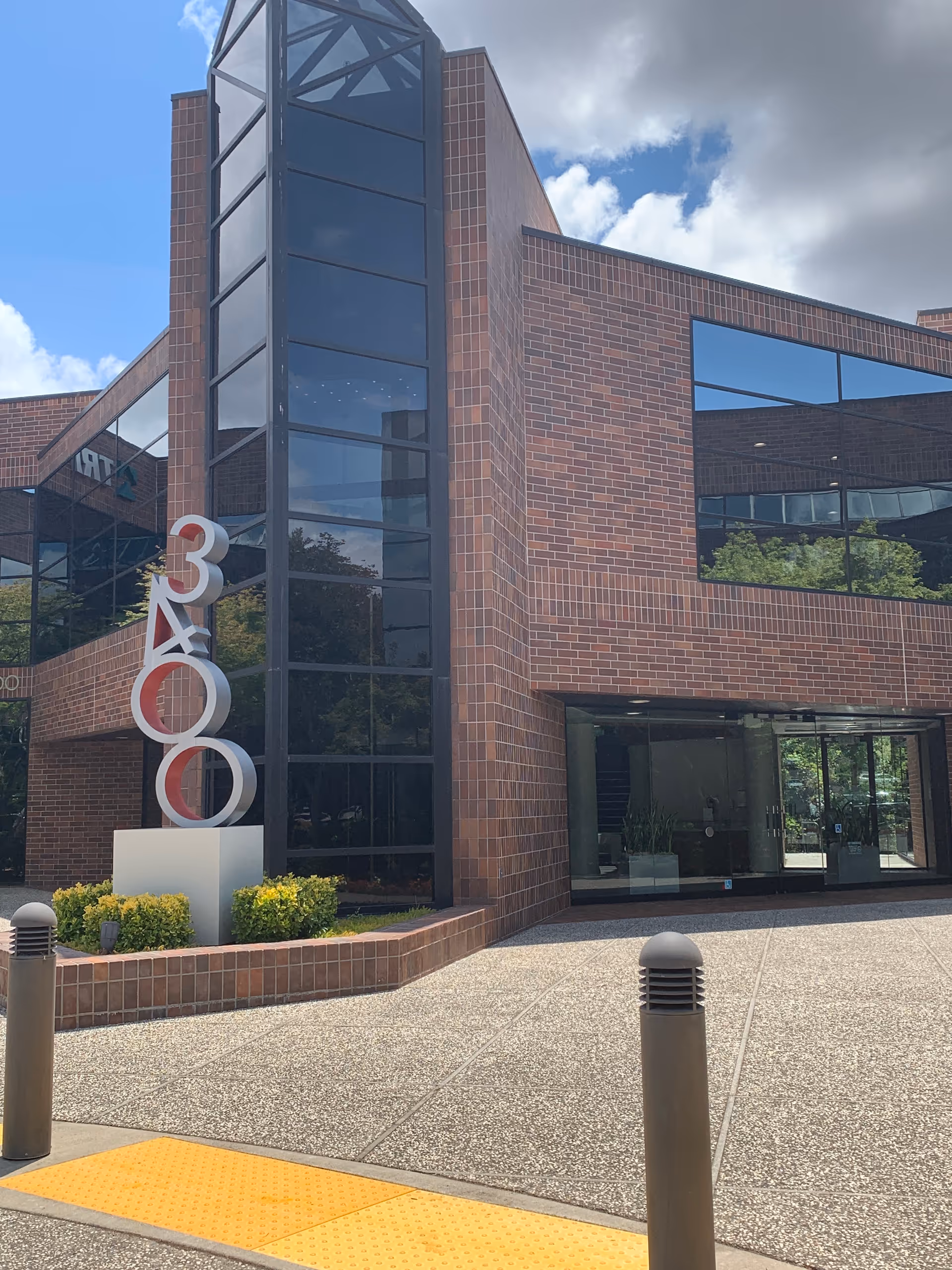 Modern brick building exterior with large glass windows and a sculptural display near entrance.