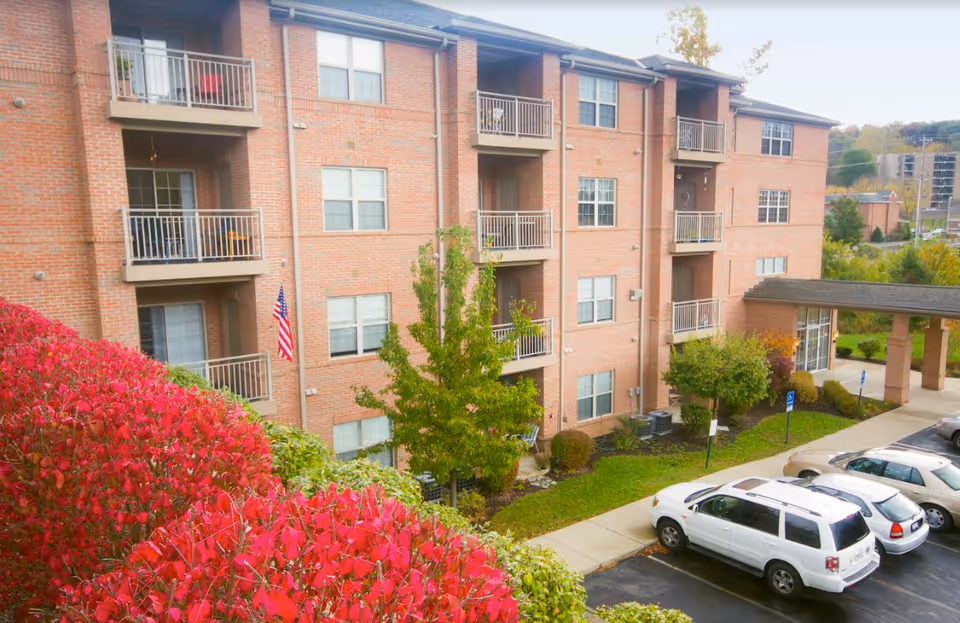 Brick multi-story National Church Residences Chillicothe exterior with balconies, landscaping, and parked cars.