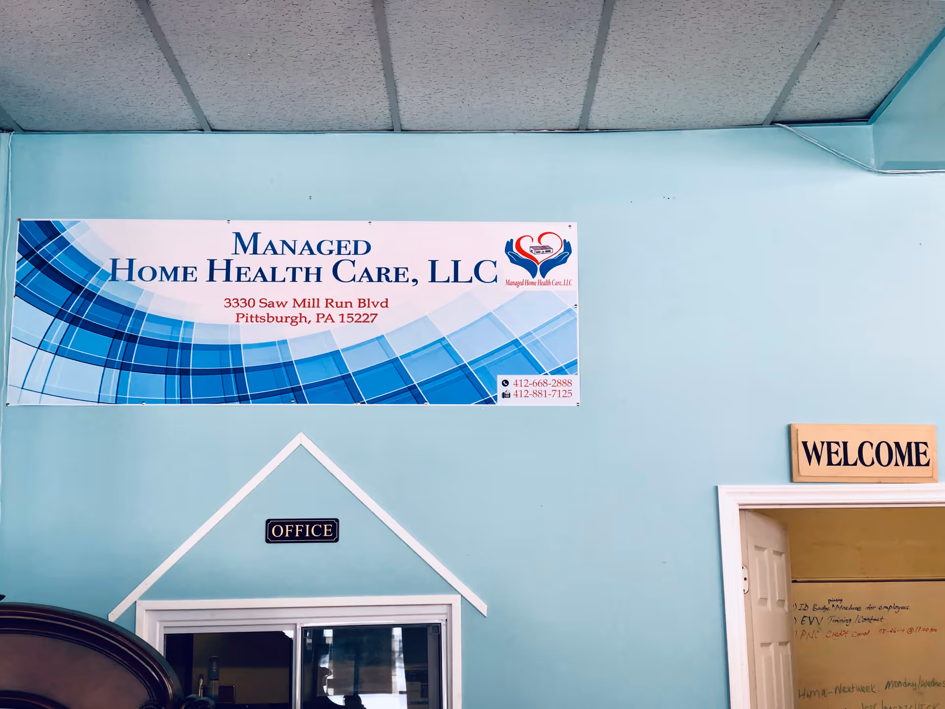 Teal interior wall with a banner for Managed Home Health Care, LLC and an office sign.
