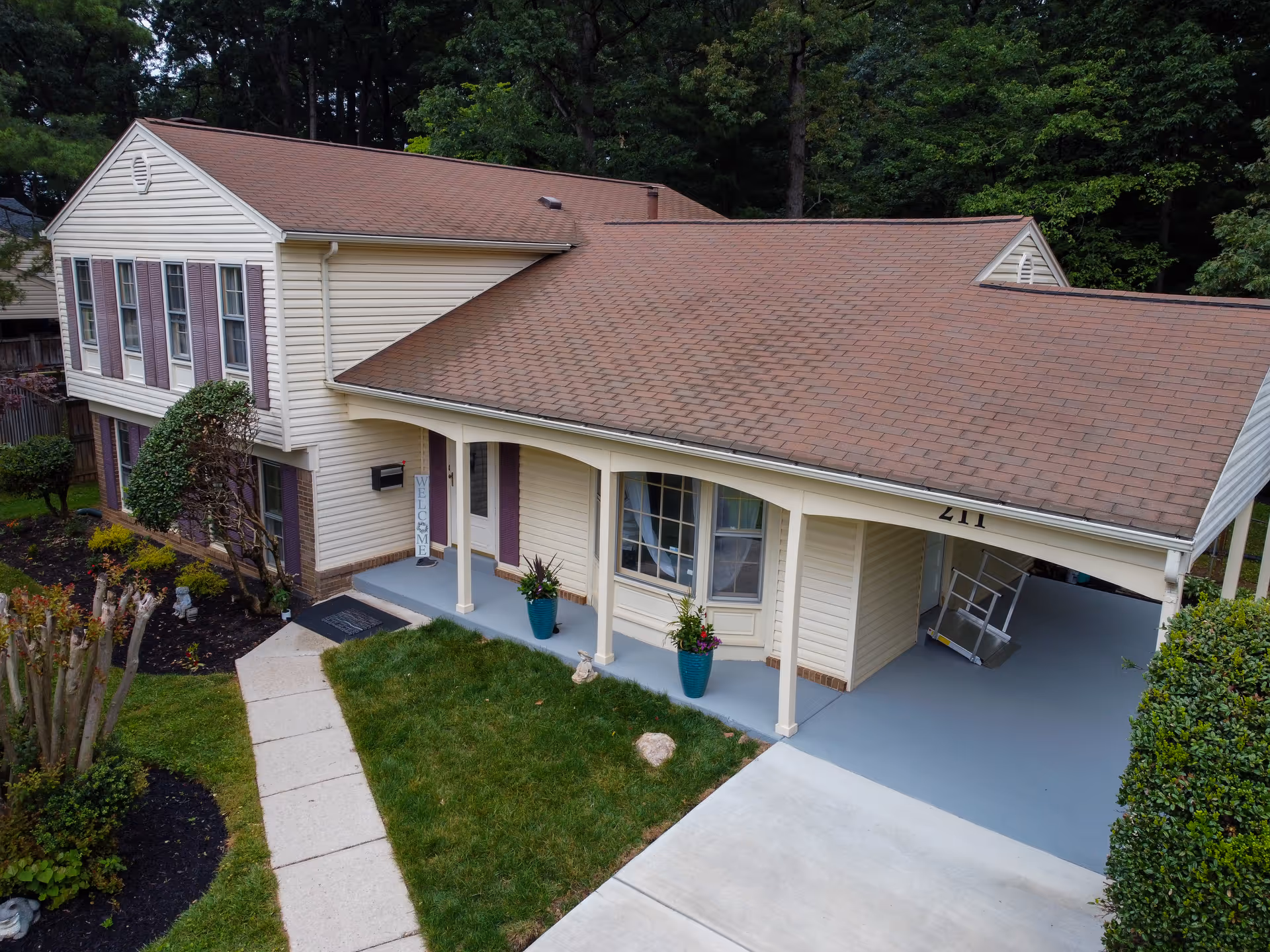 A beige, house-style assisted living building with a covered front porch and driveway.