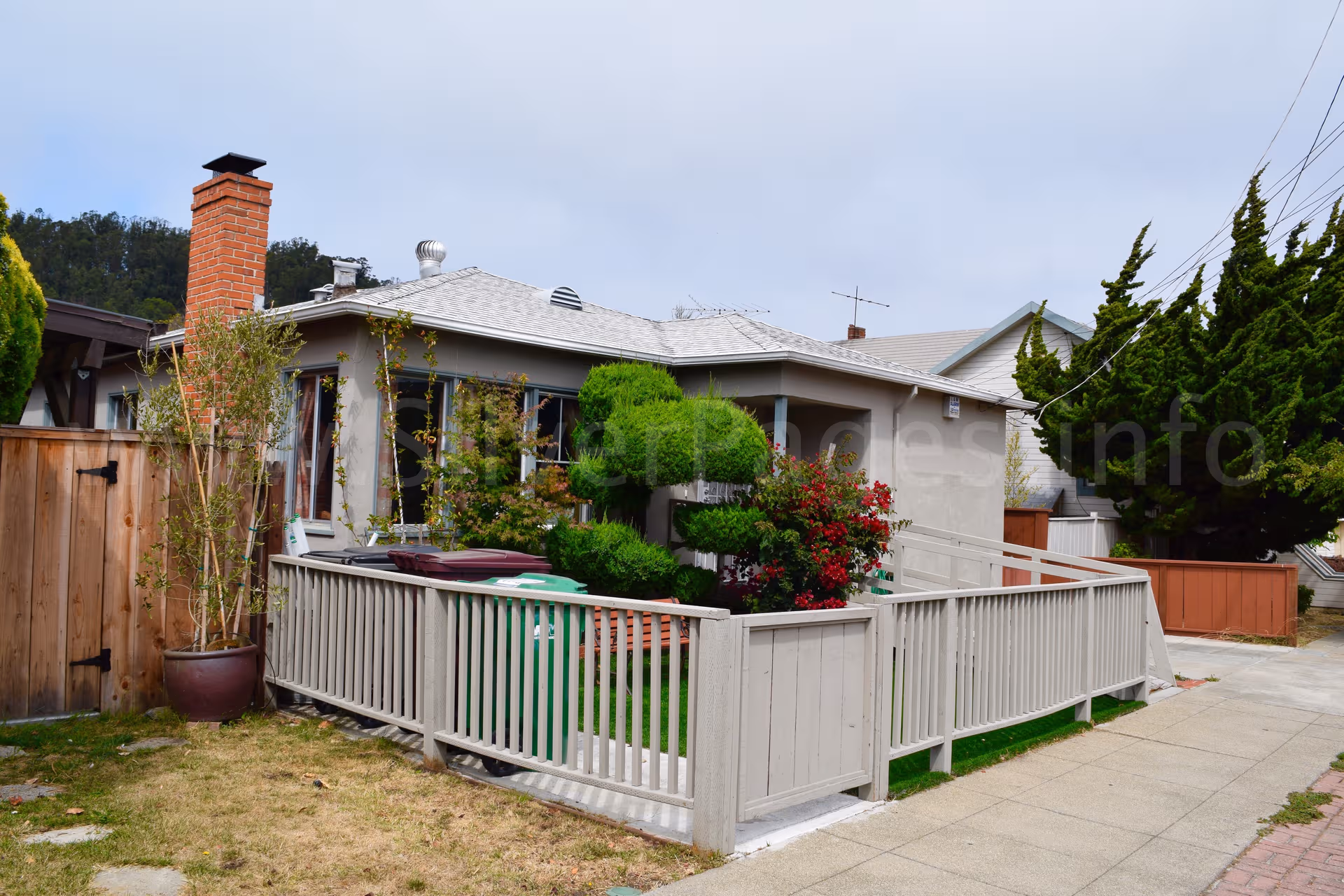 Exterior view of a single-story care home with a fenced front yard and landscaping.