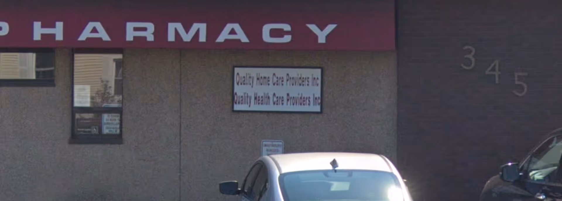 Exterior view of a building with a large pharmacy sign and Quality Home Care Providers sign.