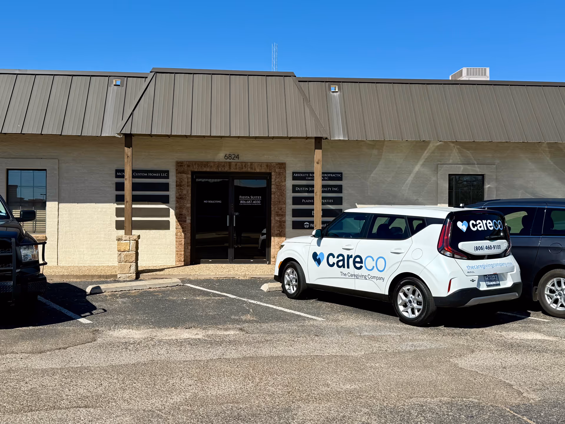 Exterior view of a beige building facade with a CareCo van parked in front.