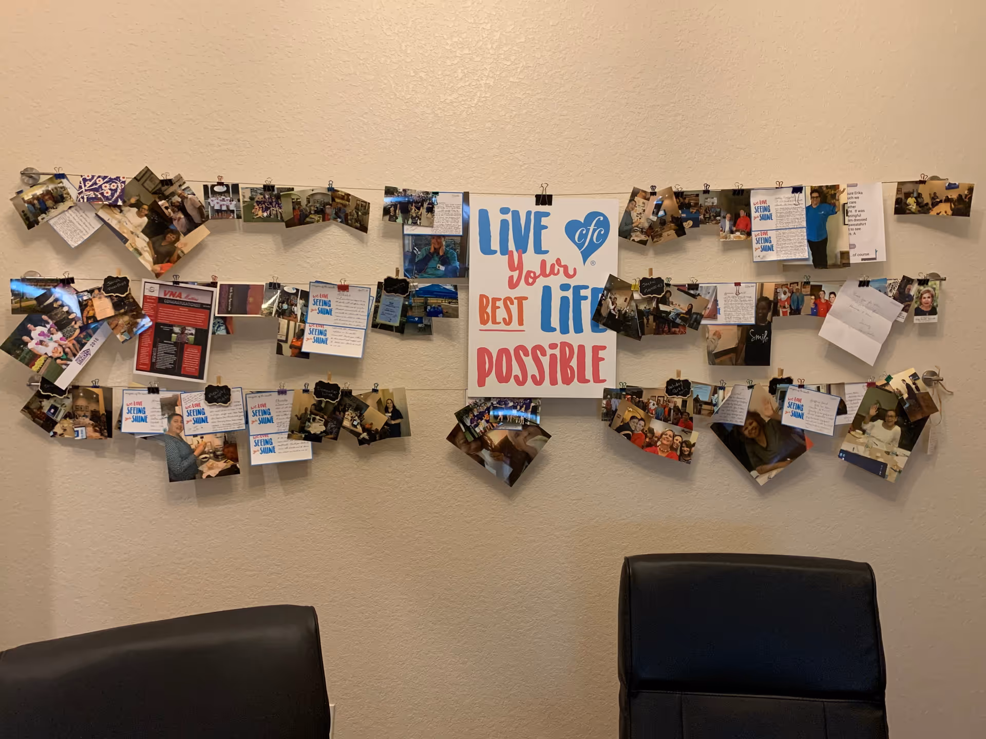 Indoor wall shows a photo collage and inspirational poster, with two black chairs underneath.