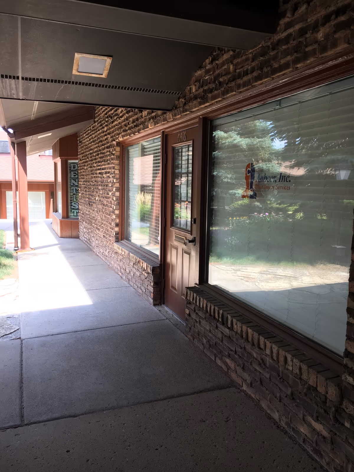 Brick exterior corridor of a senior facility with a wooden door and large window.