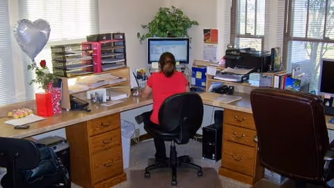 Office workspace inside a senior care facility with a staff member at a computer desk.