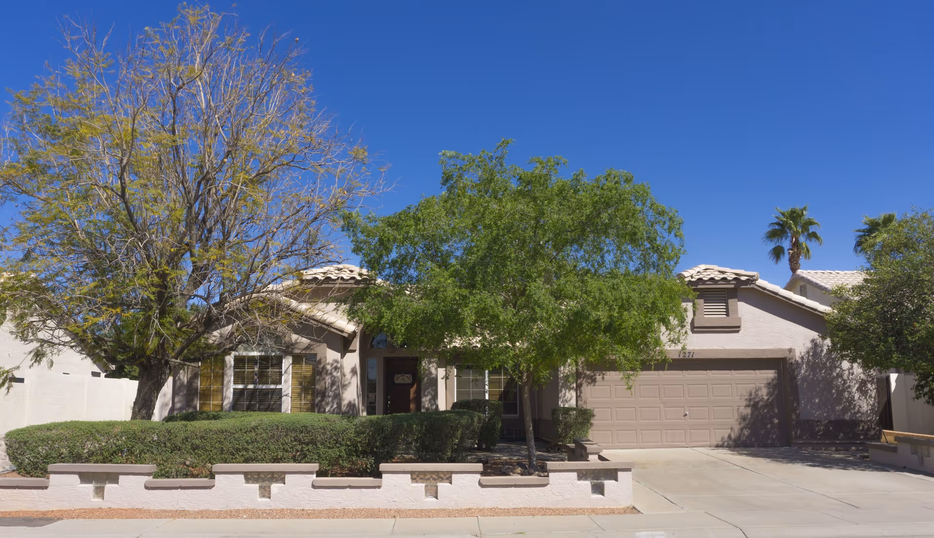 Single-story beige assisted living home with a two-car garage and green landscaping.
