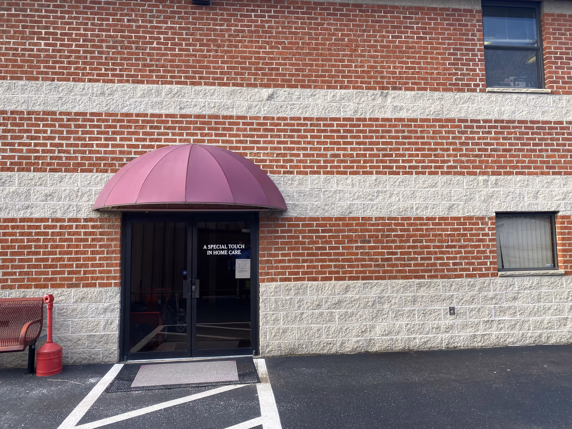 Brick building exterior with glass door under a purple awning labeled A Special Touch In-Home Care.