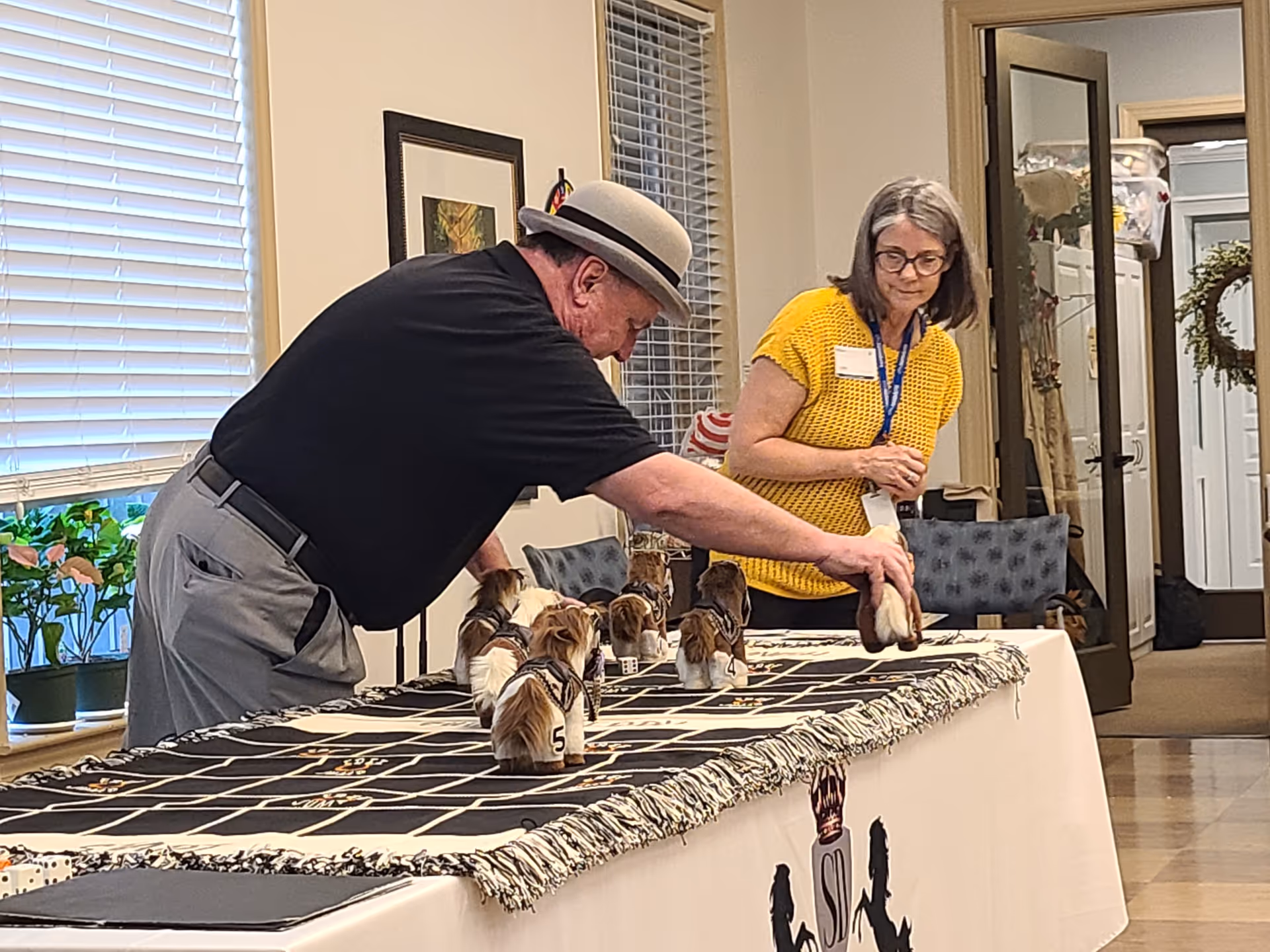 Two adults with small dogs participate in an indoor dog show on a table.