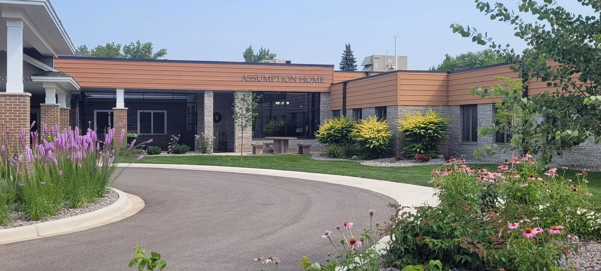 Assumption Home building facade with a curved driveway and landscaped entrance