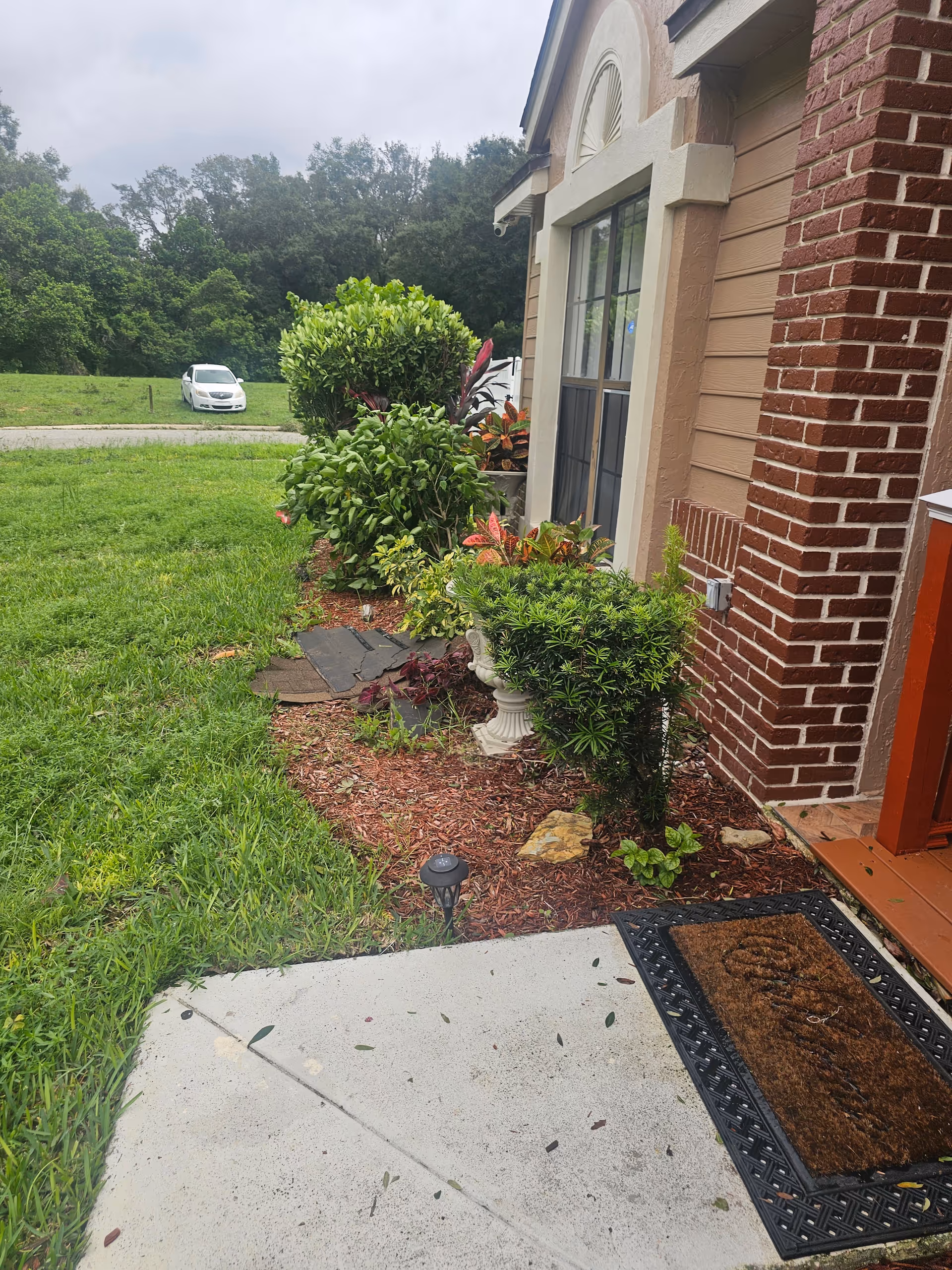Front exterior of a brick assisted living facility with landscaped walkway and greenery