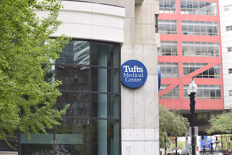 Exterior view of Tufts Medical Center building with a blue circular sign.