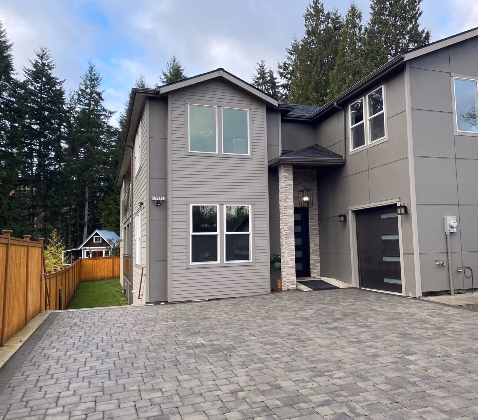 Exterior view of a modern two-story building with gray siding, windows, and a paved driveway.