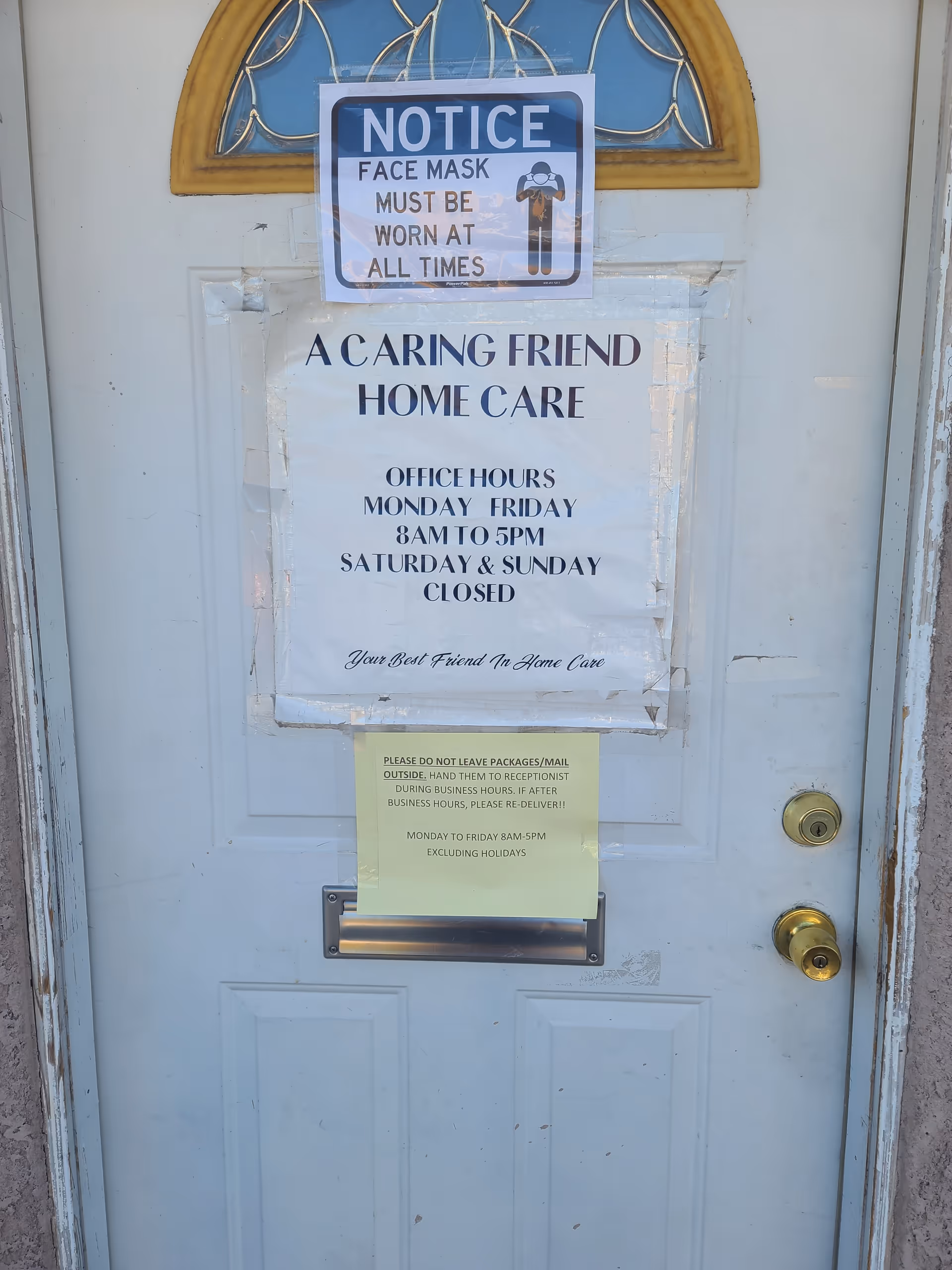 Front door of A Caring Friend Home Care with a mask notice and posted hours