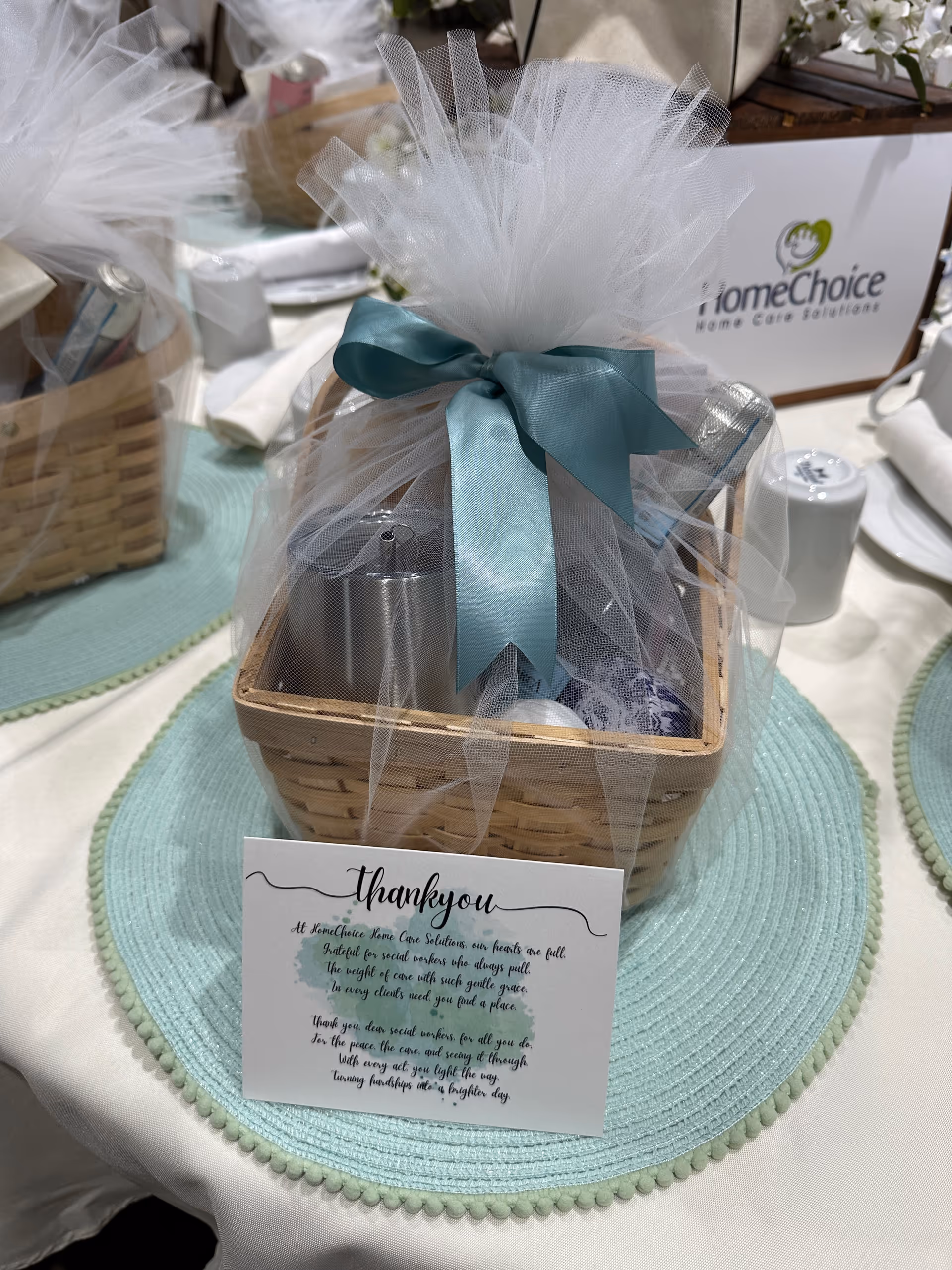 Gift basket wrapped in tulle with teal ribbon on a table at HomeChoice Home Care Solutions.