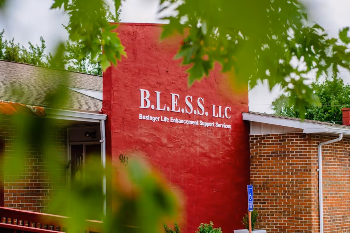 Exterior red wall sign for B.L.E.S.S. LLC on a brick senior facility.