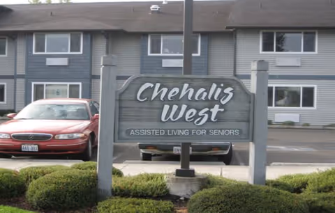 Chehalis West Assisted Living sign in front of a building with parked cars.