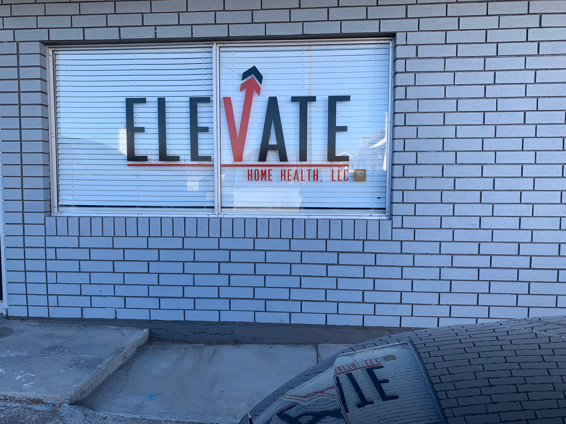Brick exterior with window sign reading Elevate Home Health LLC