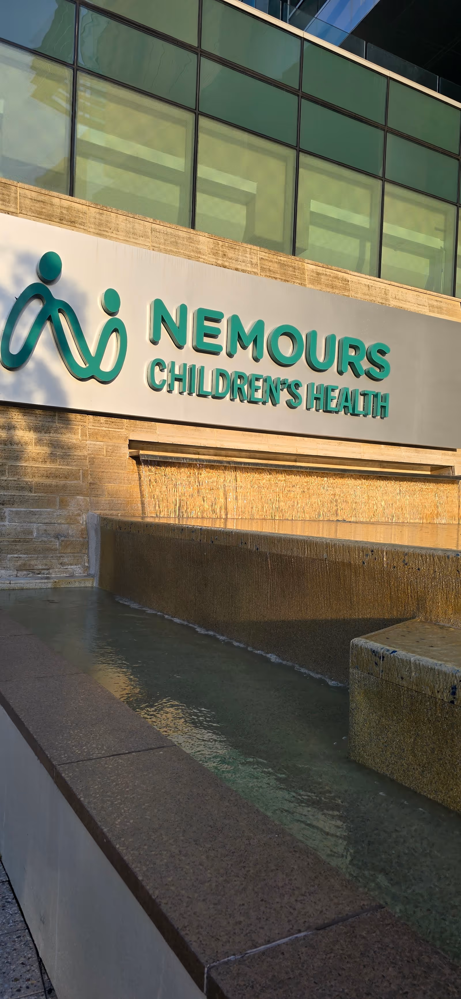 Front exterior of Nemours Children's Health facility with signage and cascading water feature.