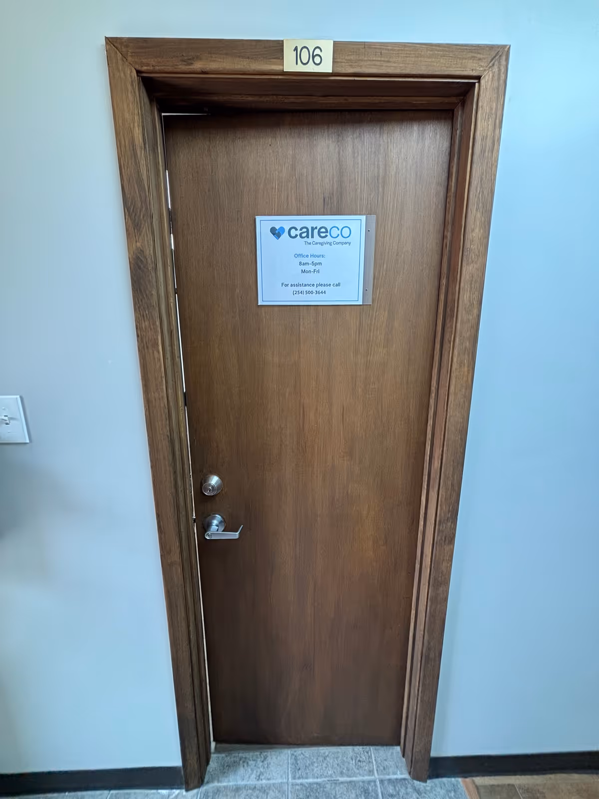 Wooden interior door with CareCo sign in a hallway, numbered 106.