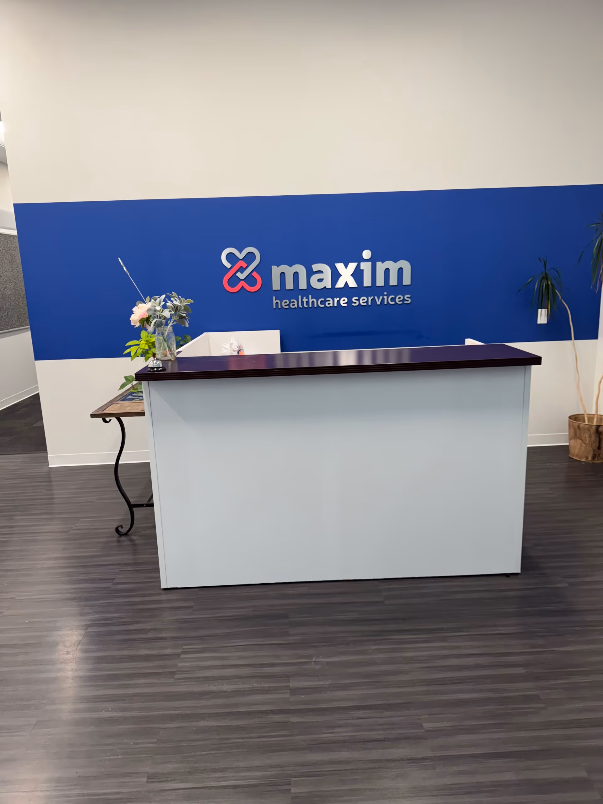 Reception desk in a modern interior with Maxim Healthcare logo on a blue wall
